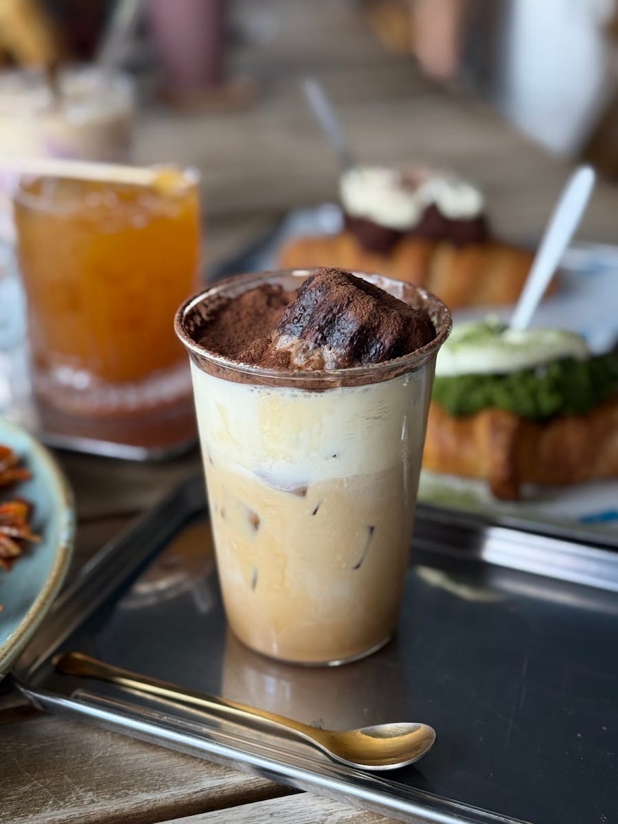 Iced coffee finished with cocoa powder on a metal tray at The Blue Door Coffee House